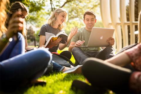 Students laptop seating on grass